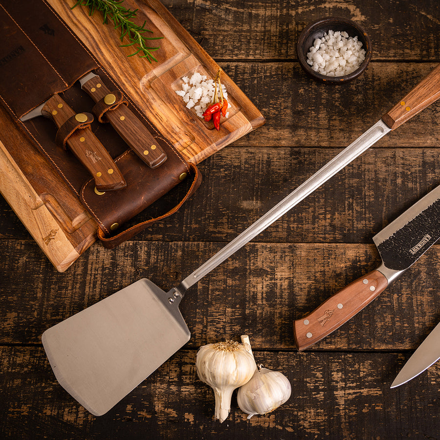 Espátula parrillera Pro XL Kangkawe sobre tabla de madera para asado