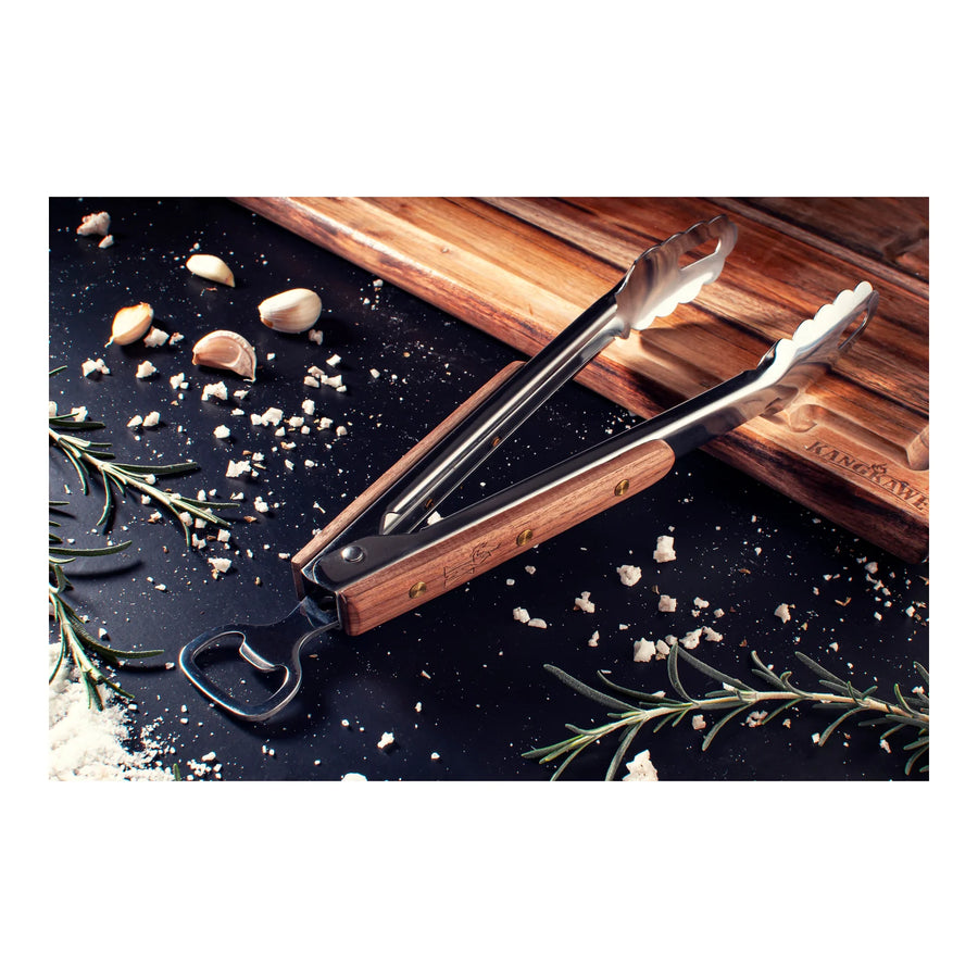 Tenaza parrillera Kangkawe sobre tabla de madera con especias para asado