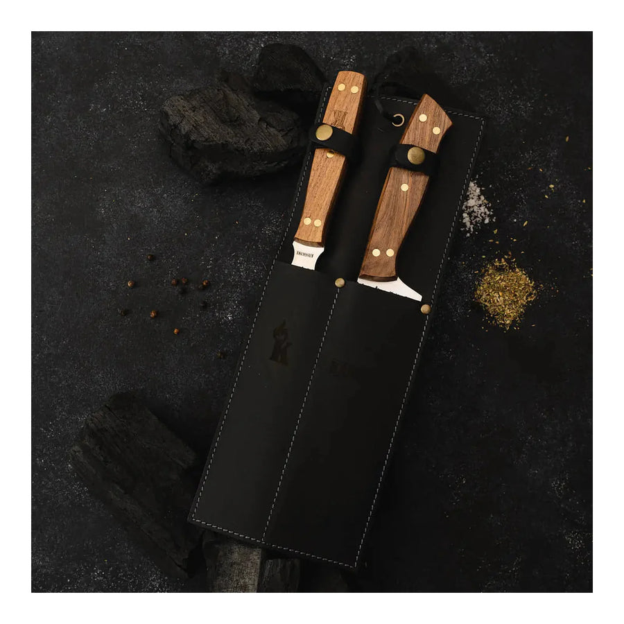 Set parrillero Kangkawe con funda de cuero negra sobre carbón de parrilla