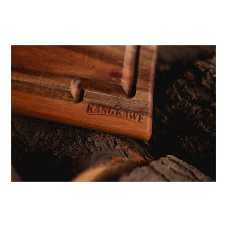 Set parrillero con tabla Kangkawe junto al fuego de la parrilla