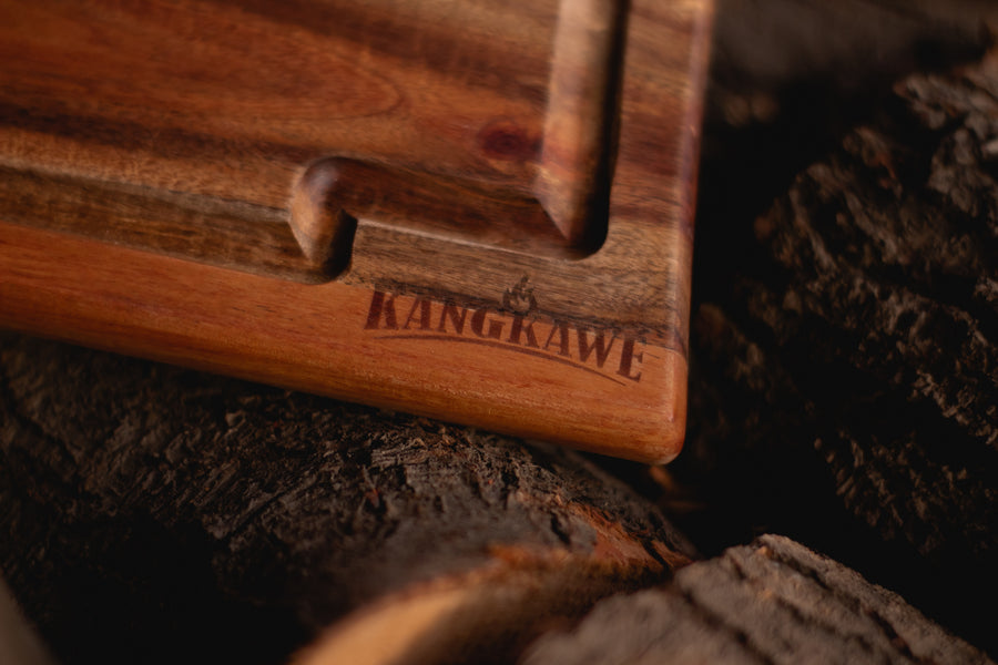Set parrillero con tabla Kangkawe junto al fuego de la parrilla