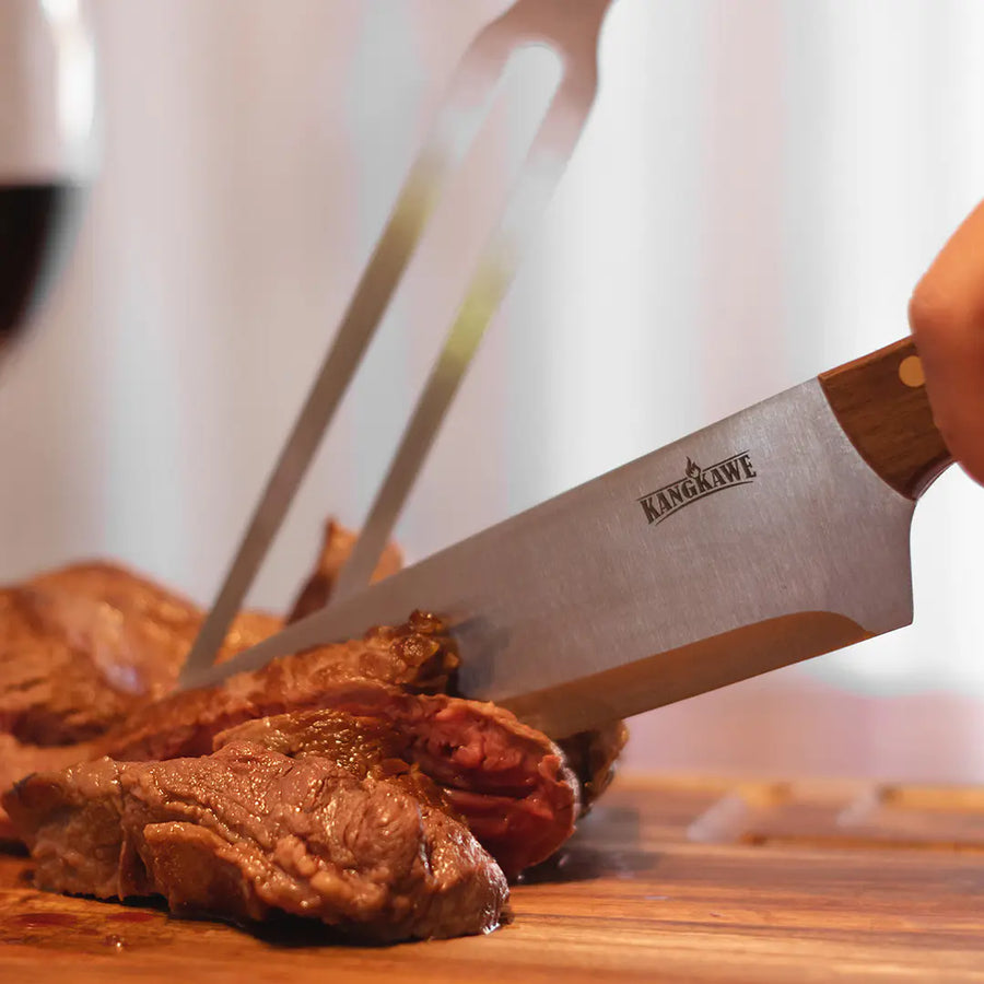 Set parrillero Kangkawe tabla, cuchillo y pincho con funda de cuero cortando carne en pleno asado